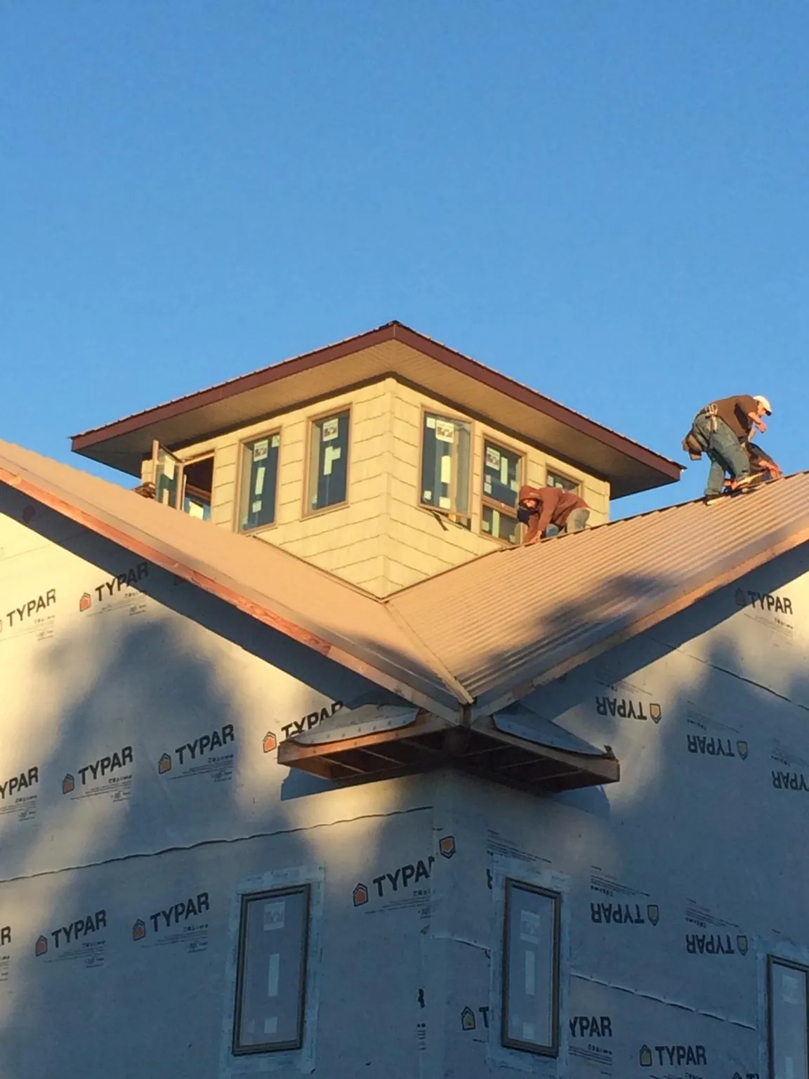 Roofers working around a rooftop cupola on a new metal roof at sunset — Roof Waterproofing in Roosevelt by Roofing Brothers
